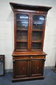 A VICTORIAN MAHOGANY BOOKCASE, with an overhanging cornice, two glazed doors, enclosing three