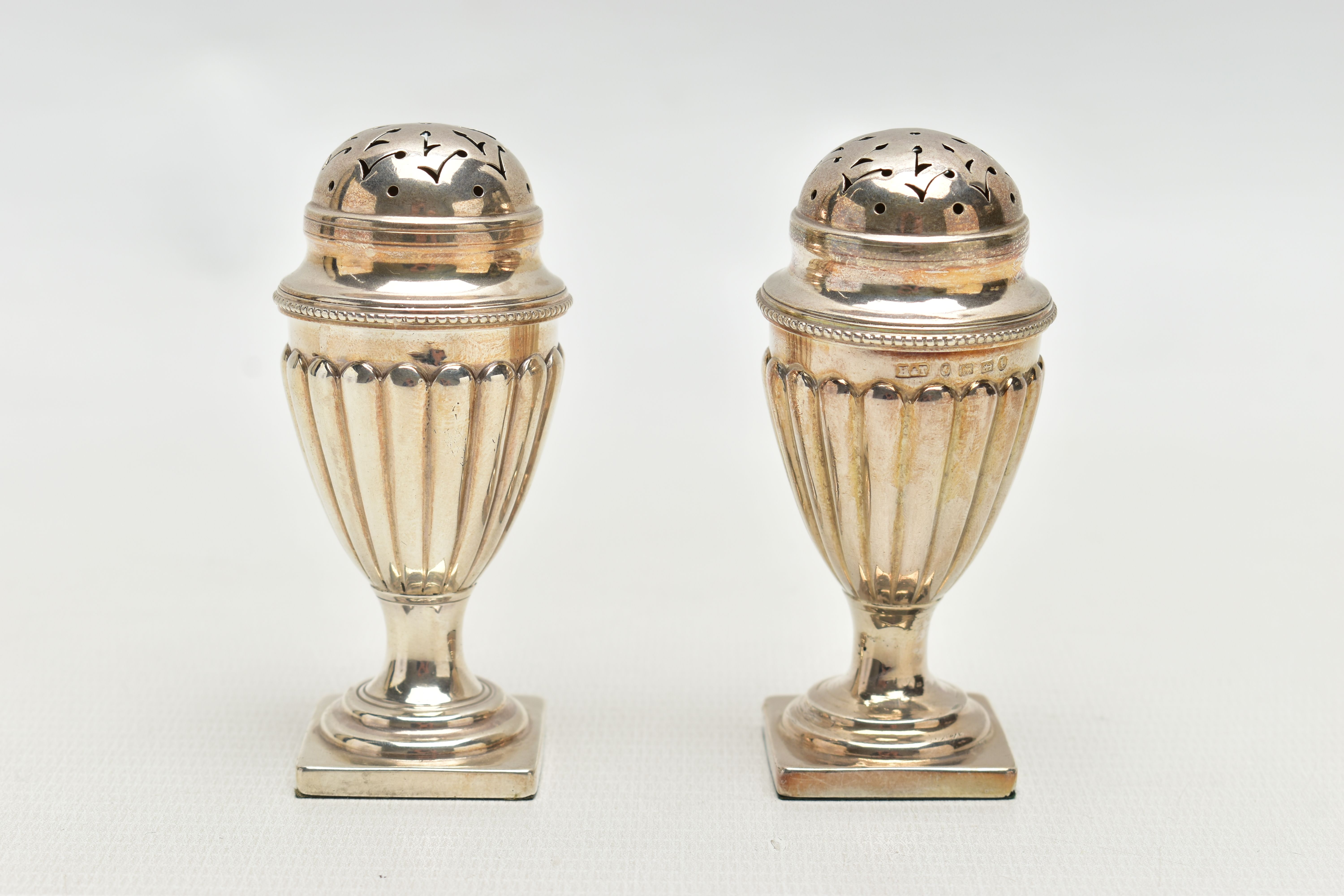 A PAIR OF VICTORIAN SILVER PEPPERETTES, each of a tapering form, stop reeded design, on weighted