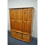 A MODERN PINE TRIPLE DOOR WARDROBE, with four drawers, width 138cm x depth 54cm x height 184cm (