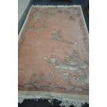 A WOOLLEN PINK CHINESE RUG, 308cm x 198cm (condition:-stained to one corner)