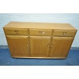 AN ERCOL BLOND SIDEBOARD, with three drawers over three cupboard doors, central drawer with