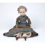 A wax over composition doll, with brown pupil-less eyes, mohair wig on cloth body with carved wooden