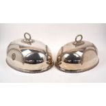 Two silver plated domed dish covers, of oval form with loop handles and gadrooned rims, designed