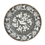 A Dagestani plate, late 19th century, decorated with hand-painted black underglaze, depicting a bird