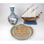 A wooden handmade sailing boat with material sails on a blue resin mount, with brass decoration,