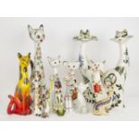 A group of pottery cats with elongated necks and pronounced whiskers, of varying size and design, to