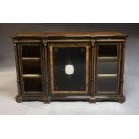 A Victorian figured walnut and ebonised credenza, with central cupboard door set with oval mirror