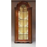 A mahogany standing corner cabinet, 19th century, with panel glazed door below break arch top,