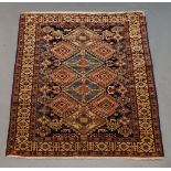 A Shirvan rug with lozenge medallions in charcoal field and with hooked border guls, 141 x 123