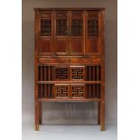 A Chinese stained wood cabinet, early 20th Century, with four pierced cupboard doors above three