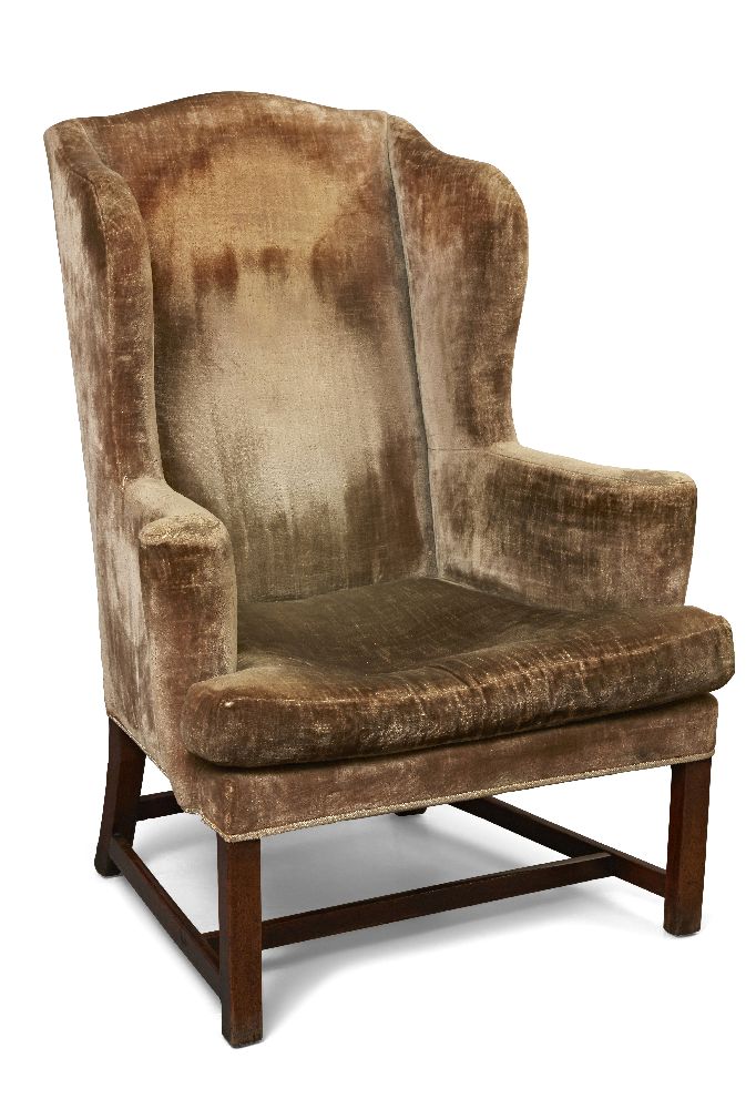 A George III mahogany wing armchair, with out-swept arms, the seat with squab, upon square legs