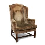 A George III mahogany wing armchair, with out-swept arms, the seat with squab, upon square legs