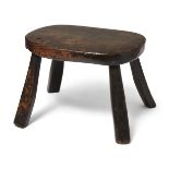 An ash and fruitwood milking stool, probably Welsh, early 19th century, with four out-swept legs,