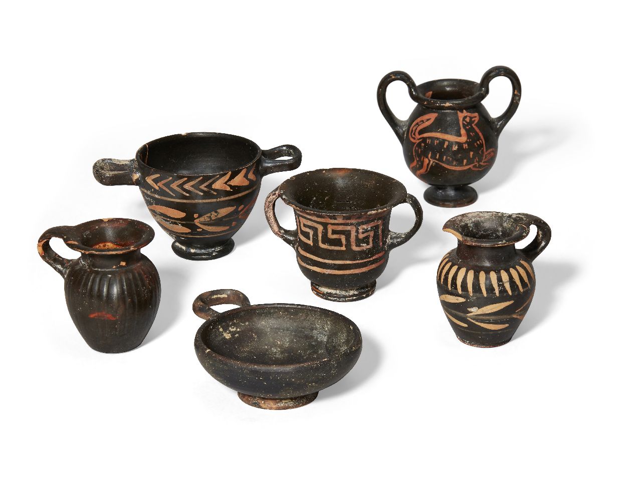 Six miniature Apulian black glazed pottery vessels, including four with applied red decoration; a