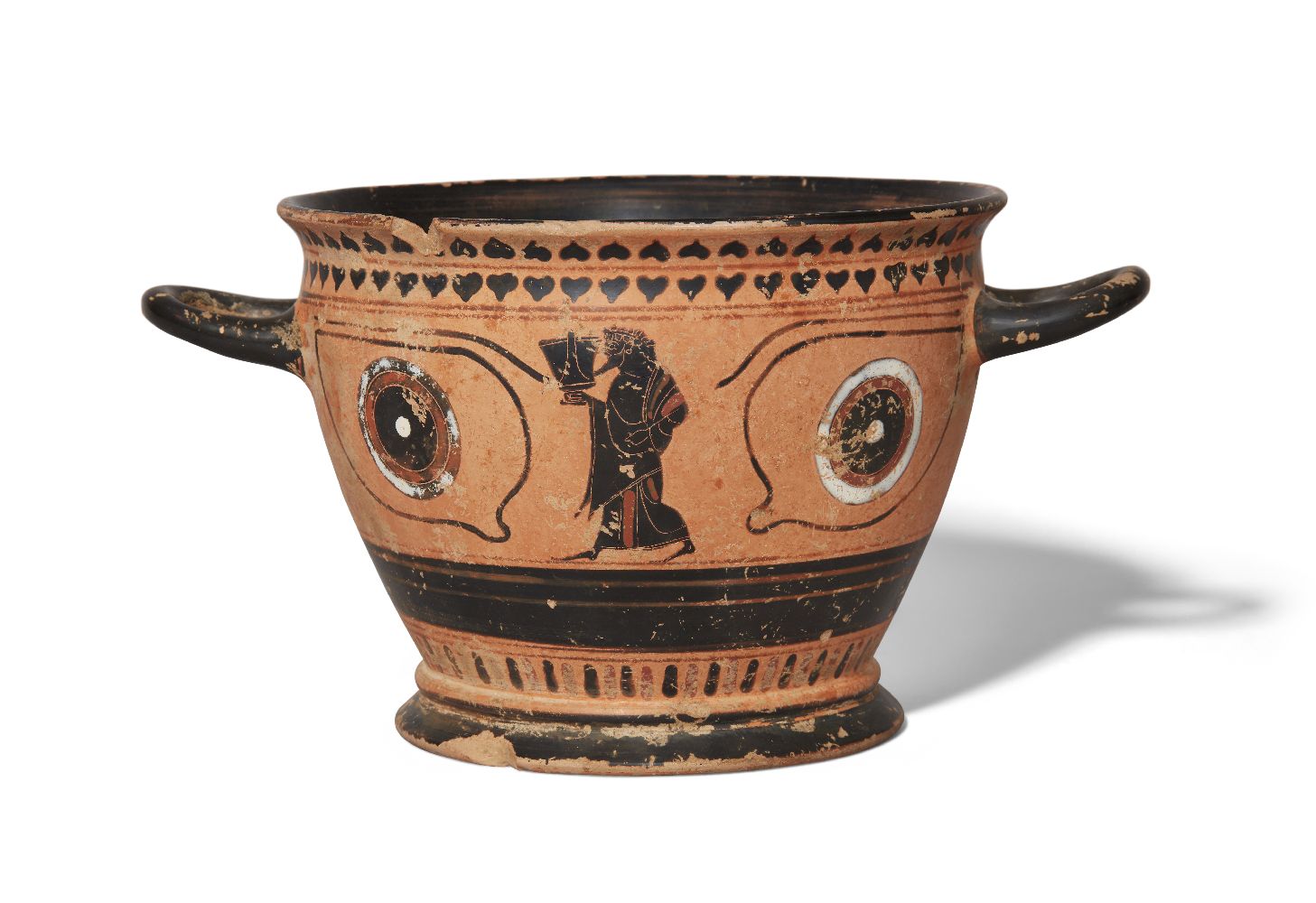 A Greek style black-figure eye cup, one side decorated with a dancing satyr holding a skyphos, the