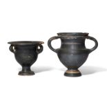 A black glazed kantharos on a pedestal base with two conjoined strips forming each handle, faint