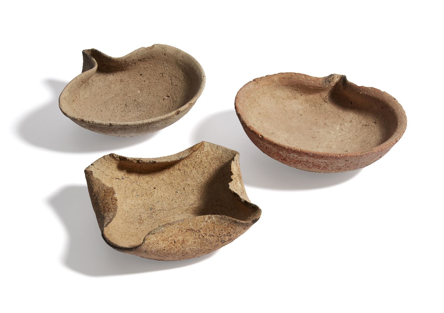 Three buff pottery open-wicked oil lamps, two with round bowl and pinched in wick-holes, 14cm and