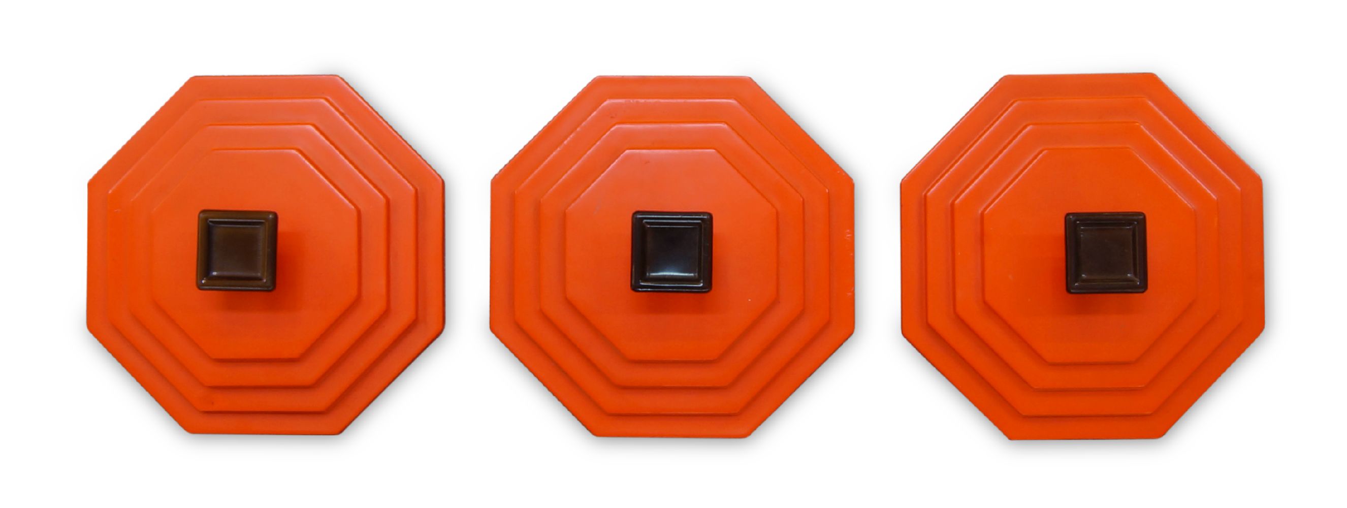 A set of three orange plastic and wall mounted coat hooks, c.1960, Of stepped octagonal form, with