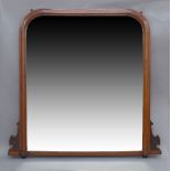 An Art Nouveau mahogany over mantle mirror, with rounded top, carved floral motifs, raised on ball