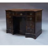 A George III serpentine mahogany and crossbanded knee hole desk, with nine drawers about a