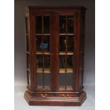 An Indian hardwood cabinet, the moulded cornice above two astragal glazed doors, enclosing three