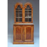 A George II style walnut bookcase, early 20th century, the twin arched top above pair of glazed