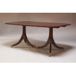 A Regency style mahogany twin pedestal dining table, the three-section solid top on a pair of gun