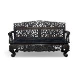 A Chinese hardwood settle, late 19th century, with profusely carved and pierced back decorated