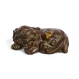 A Chinese gold-splashed bronze 'lion' scroll weight, 19th century, modelled in a recumbent pose with