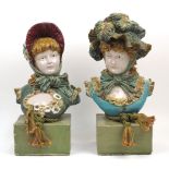 A near pair of Continental porcelain busts of young women wearing bonnets, on later bases, one