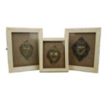 Three display frames containing various white metal plaques, one stamped 800 for continental silver,