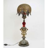 A large table lamp, 20th century, three bulb with domed filigree white metal shade and red cut glass