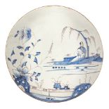 A Delft Chinoiserie charger, early 19th century, decorated with a river landscape with a figure