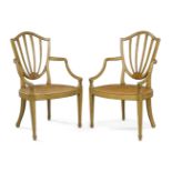 A pair of George III painted caned elbow chairs, circa 1790, the shield shape back rests hand