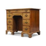 A George III mahogany kneehole desk, with frieze drawer above recessed cupboard flanked by six