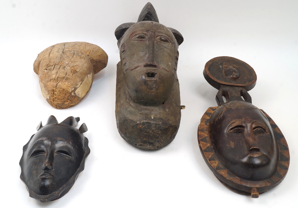 Four African masks, to include a mask with elaborate coiffure, possibly Yaure, 45cm high; a