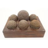 Six iron studded balls, probably for the French game of Petanque, in fitted wooden stand, 31cm