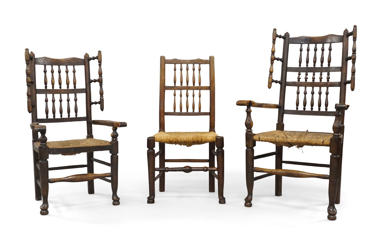 A near pair of oak wing back armchairs, 18th century, with turned spindle back rests and rush seats,