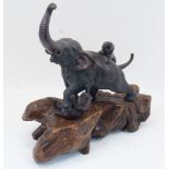 A Japanese bronze elephant, Meiji period, modelled with trunk raised and stepping on a panther