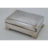 A silver cigarette box, marks rubbed, with striped engine turned cover having cartouche with