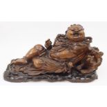 A Chinese hardwood carving of Hotei, early 20th century, carved in reclining pose with lion dog,