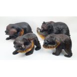 A group of four Japanese carved wood models of brown bears, 20th century, each with a fish in its