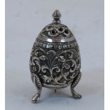 A white metal salt shaker, Kutch India, on three raised feel, deeply engraved with flower heads