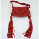 Alexander McQueen: a red leather fringed shoulder sable bag, with magnetic faux buckle flap closure,