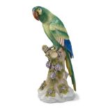 A Continental porcelain parrot, late 19th century, perched on a floral encrusted tree stump, bearing