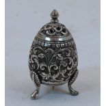 A white metal salt shaker, Kutch India, on three raised feel, deeply engraved with flower heads