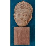 A Khmer terracotta head of a deity, Srivijava period, 7th-12th century, 12cm high, on wood stand
