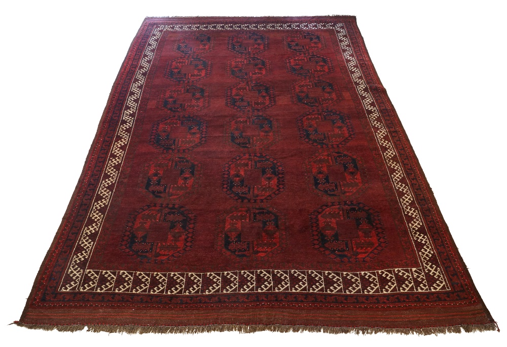 An Afghan bokhara carpet, c.1910, the rich aubergine ground with repeating gul motifs within