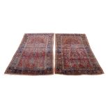 A pair of central Persian Sarouk rugs, 20th century, with vase of flowers central design, on a red