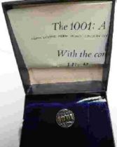 A lapel pin for The 1001: A Nature Trust, depicting a globe in gilt relief with blue enamel and 1001
